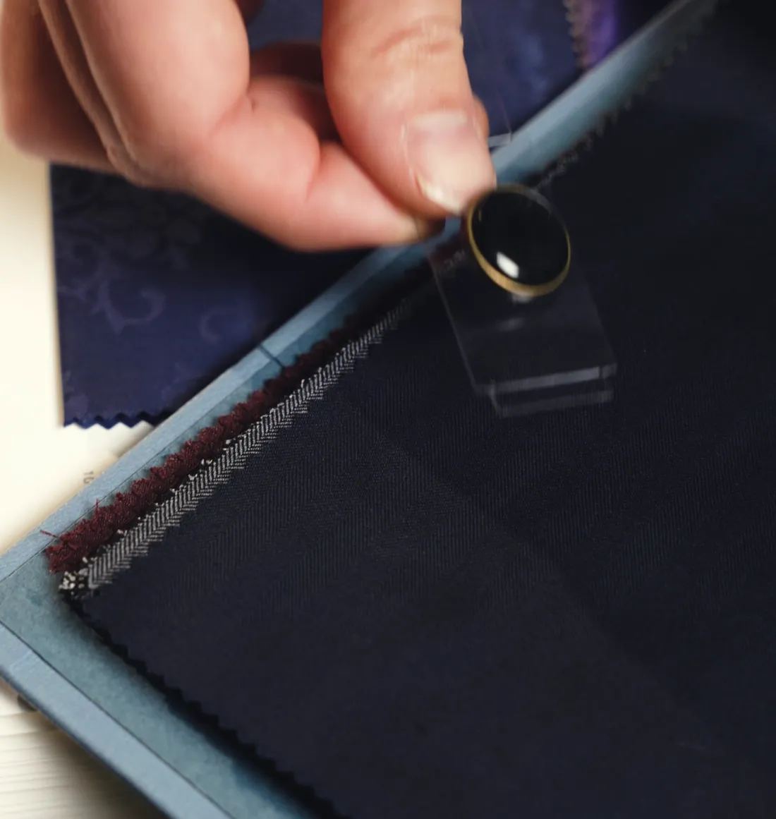 Choosing a button against the cloth, swatch book open